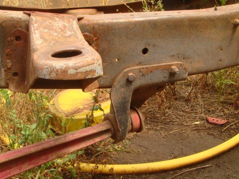 1992 Ford Bronco - Close-up of heavily rusted vehicle frame components, including a tow hitch bracket and suspension parts.