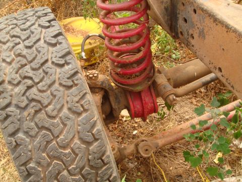 1992 Ford Bronco - Close-up of a vehicle's front suspension system, a red coil spring and a portion of the tire.