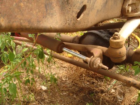 1992 Ford Bronco - Close-up view of the undercarriage, showing rusty steering components and a shock absorber.