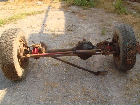 1992 Ford Bronco - A front axle assembly with tires and suspension components is shown on a gravel surface.