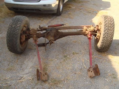 1992 Ford Bronco - Front axle assembly with tires and red shock absorber, likely for an off-road vehicle.