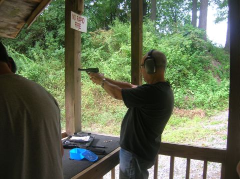 1996 Ford Bronco - A shooter takes aim at an outdoor range, with a sign reminding participants to avoid rapid fire.