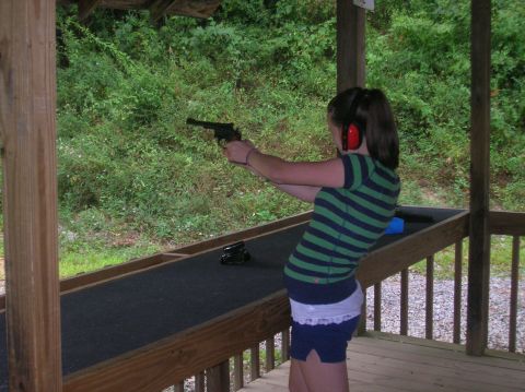 1996 Ford Bronco - A young woman practices her aim at an outdoor shooting range, wearing protective earmuffs.