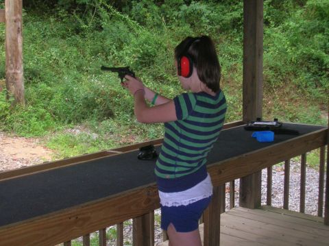 1996 Ford Bronco - A young person practices shooting a handgun at an outdoor range with trees in the background.