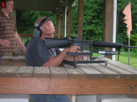 1996 Ford Bronco - A man practices shooting a rifle at an outdoor range while another person observes.