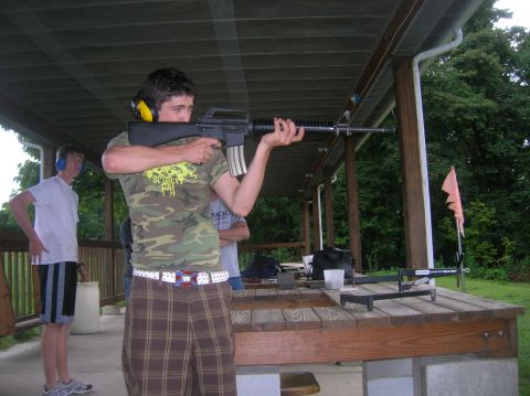 1996 Ford Bronco - A man practices shooting at an outdoor range, wearing ear protection and camouflage clothing.