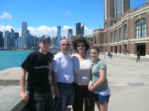 1996 Ford Bronco - A family poses for a photo with a city skyline and a large brick building behind them on a sunny day.