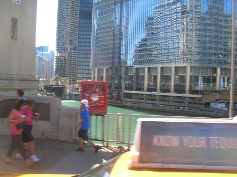 1996 Ford Bronco - A view of a city skyline with a river and people walking by, with a taxi in the foreground.