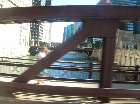 1996 Ford Bronco - A person walks along a bridge overlooking the Chicago River, with city buildings in the background.