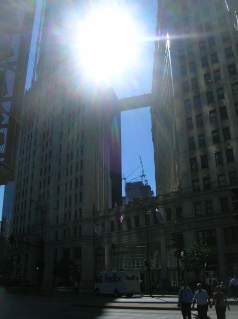 1996 Ford Bronco - A bright sun shines between two large buildings in a city, with a FedEx truck visible on the street.