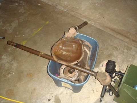 1992 Ford Bronco - Axle shafts and a differential cover are stored in a blue bin on a concrete floor.