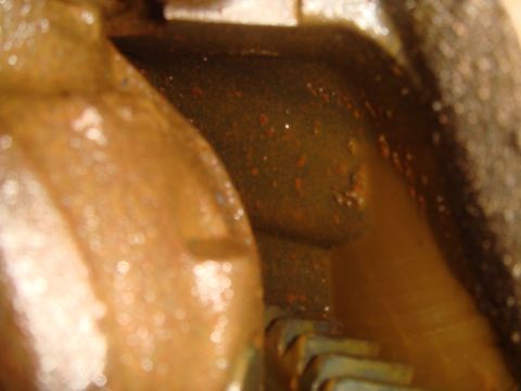 1992 Ford Bronco - This image shows a close-up of an engine oil pan, revealing a significant amount of debris and metal shavings within the oil.