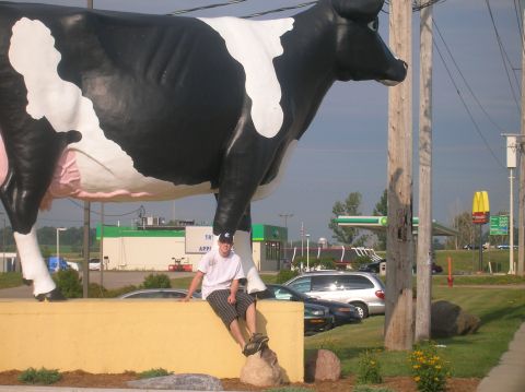 1996 Ford Bronco - A person poses next to a giant cow statue with a gas station and fast food restaurant in the background.