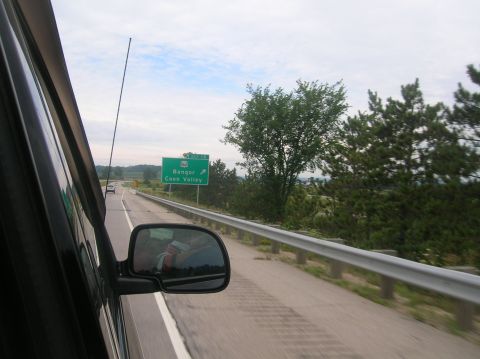 1996 Ford Bronco - View from a car's passenger seat shows a highway scene with a directional sign and trees.