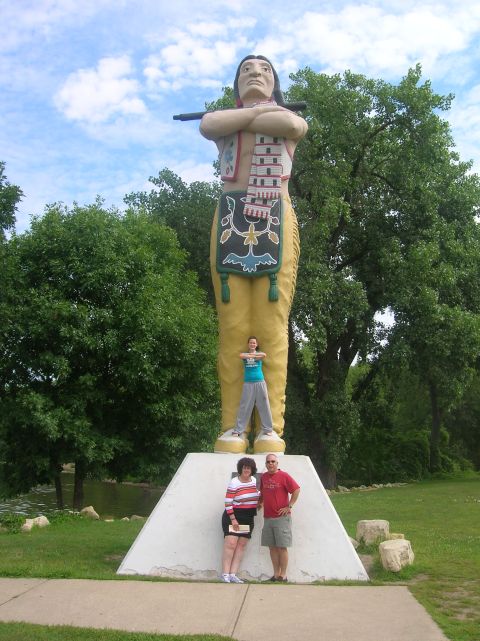 1996 Ford Bronco - A family poses with a giant statue of a Native American holding a pipe in a park setting.