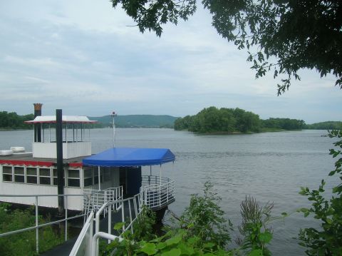 1996 Ford Bronco - A riverboat is moored at a dock on a wide river under a cloudy sky.