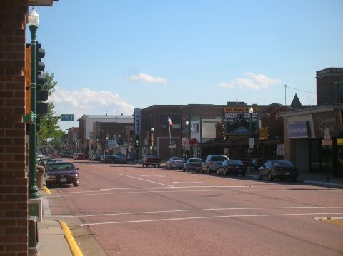 1996 Ford Bronco - A view down a street lined with buildings and parked cars on a sunny day.