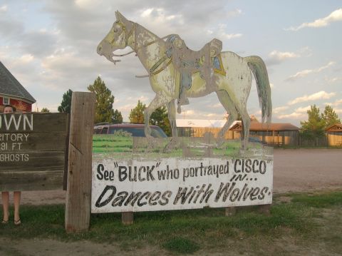 1996 Ford Bronco - A weathered sign depicts a horse, with text referencing the movie 'Dances With Wolves', set against a backdrop of a rural landscape.
