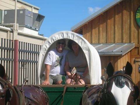 1996 Ford Bronco - A couple enjoys a ride in a horse-drawn wagon in front of a wooden building.