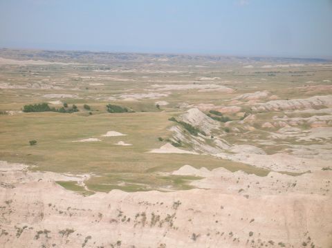1996 Ford Bronco - A vast expanse of eroded hills and grasslands stretches towards the horizon under a pale blue sky.
