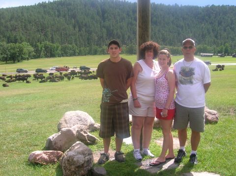 1996 Ford Bronco - A family poses for a photo with a herd of bison and a road full of cars in the background.
