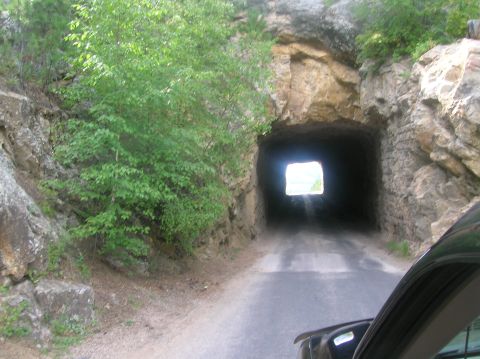 1996 Ford Bronco - Driving towards a tunnel carved into a rocky mountainside, with vegetation flanking the entrance.