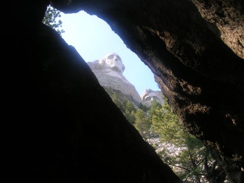 1996 Ford Bronco - The presidential faces carved into the mountain are visible through a natural rock archway.