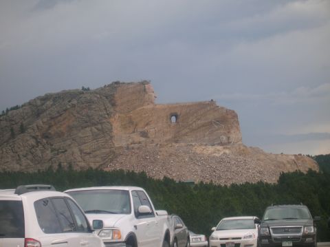 1996 Ford Bronco - Cars parked in front of the Crazy Horse Memorial under a cloudy sky.