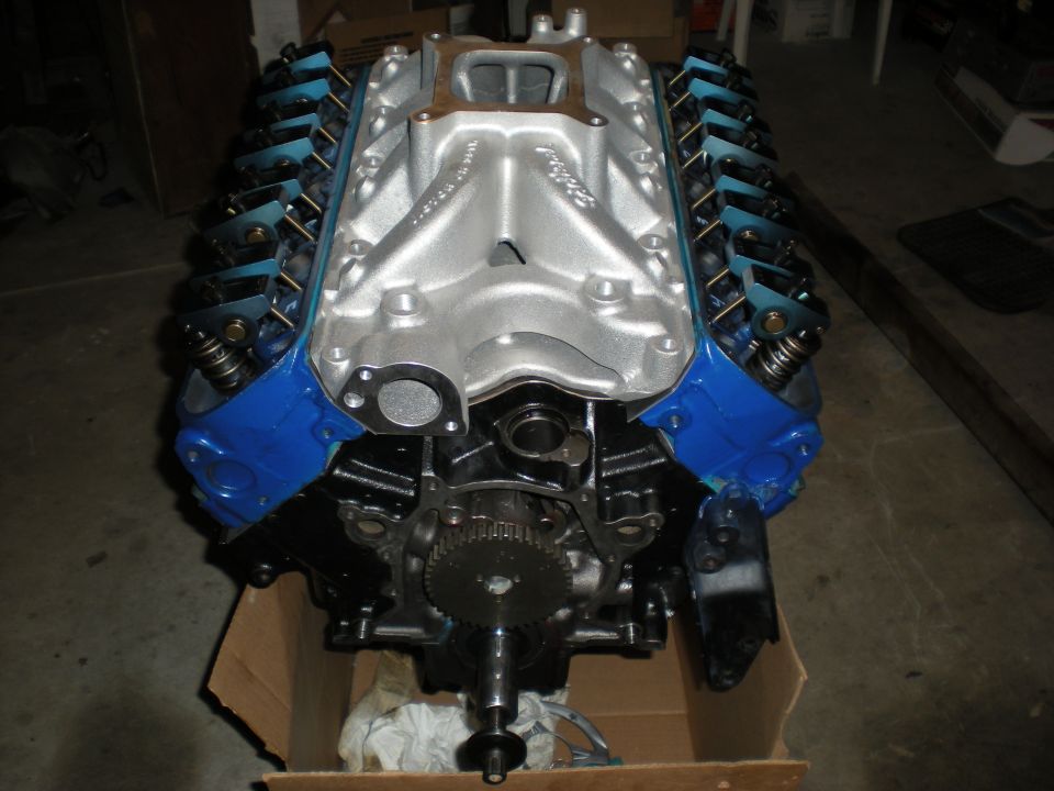 V8 engine with blue valve covers and silver intake manifold, sitting in a cardboard box
