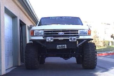 1991 Ford Bronco - This lifted Ford F-Series truck features a custom bumper and oversized tires, with a visible Ford emblem on the grille.