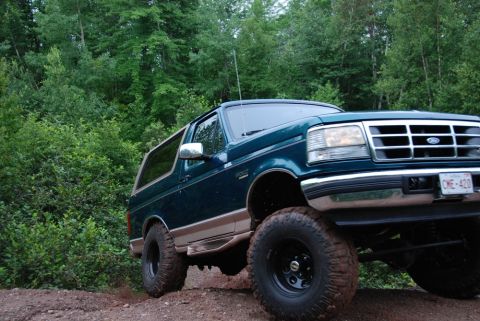 1996 Ford Bronco - This 1996 Ford Bronco is shown off-roading on a dirt path surrounded by trees.