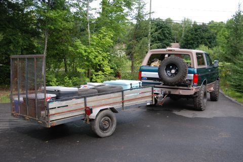 1996 Ford Bronco - A green 1996 Ford Bronco is seen from the rear, towing a utility trailer loaded with items.