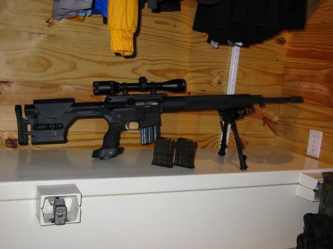 1996 Ford Bronco - A sniper rifle equipped with a scope, bipod, and two extra magazines is displayed on a shelf.