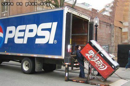 1988 Mercury Grand Marquis - A Pepsi truck is parked while a Coca-Cola vending machine is being unloaded from its back.