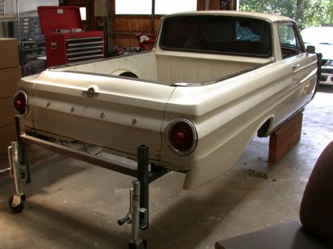 1964 Ford Ranchero - Rear view of a 1964 Ford Ranchero, likely undergoing restoration, supported by a metal stand.