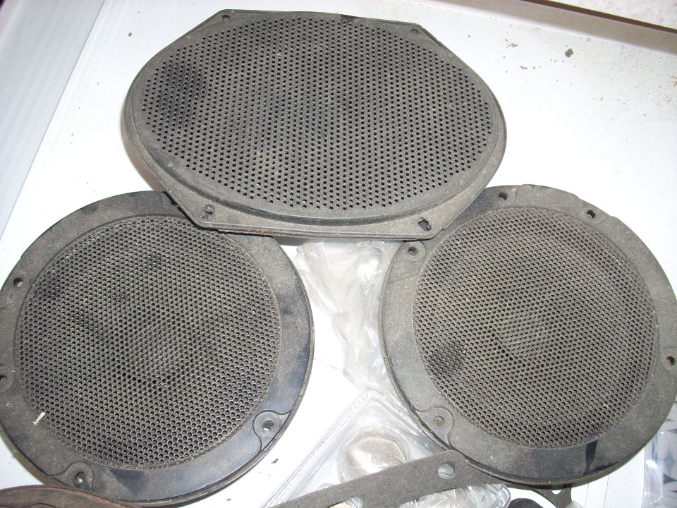 Three dusty car speakers, one oval and two round