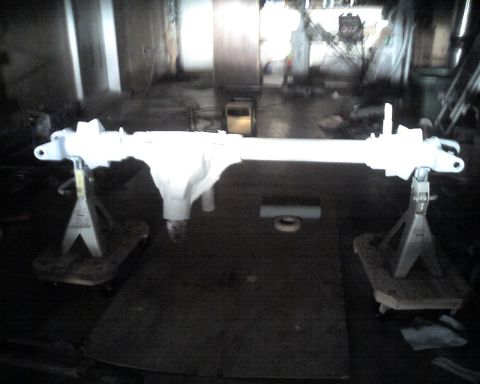 1992 Ford Bronco - A vehicle's front axle assembly is shown mounted on jack stands, likely undergoing restoration or modification.