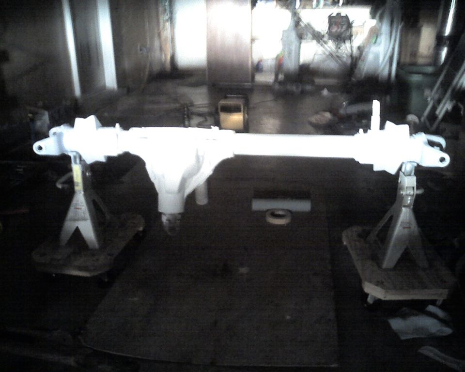 White painted front axle assembly on jack stands in a workshop