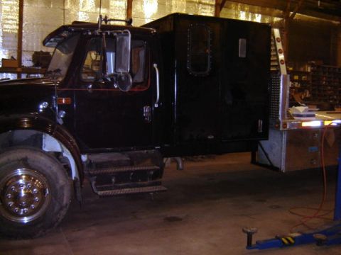 1992 Ford Bronco - A custom truck with a sleeper cab and flatbed is parked indoors.