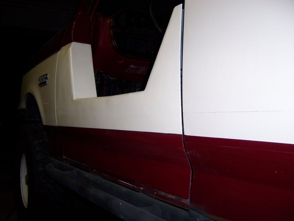 Side view of a red and white Suzuki Samurai with the door removed