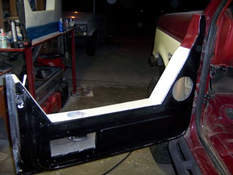 1991 Ford Bronco - Interior view of a red vehicle with an open door, showing speaker cutouts and a partially visible two-tone vehicle in the background.