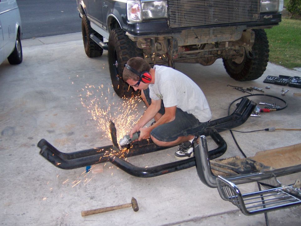 Guy grinding on a metal tube in front of a 1991 Ford F-Series truck