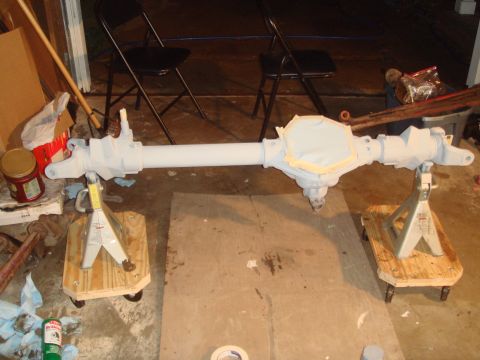 1992 Ford Bronco - A differential axle assembly, taped and primed, rests on jack stands in a garage setting.