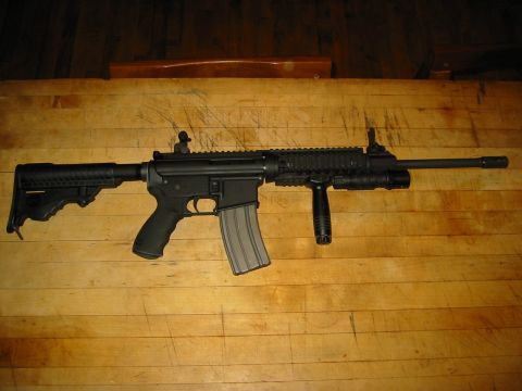 1996 Ford Bronco - A black rifle with a magazine is displayed on a wooden table.