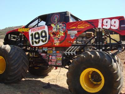 1987 Ford Bronco - A custom monster truck with oversized wheels and a red exterior is shown from a three-quarter front angle.