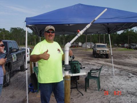 1992 Ford Bronco - Man poses with a PVC pipe contraption at an outdoor event with vehicles in the background.