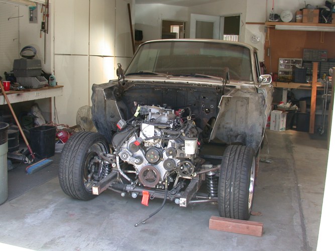 Classic car in garage with front clip removed, modern V8 on tubular crossmember and coilovers