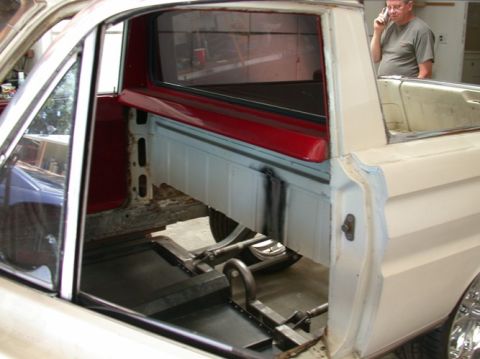 1964 Ford Ranchero - The interior and bed of a 1964 Ford Ranchero are visible, showing its white exterior and red accents.