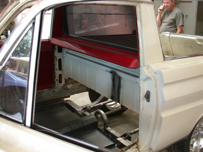 Stripped car-based pickup bed with floor removed exposing leaf springs during restoration
