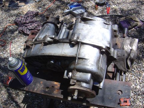 1986 Ford Bronco II - A transfer case sits on a workbench, with a can of WD-40 and some tools in the background.